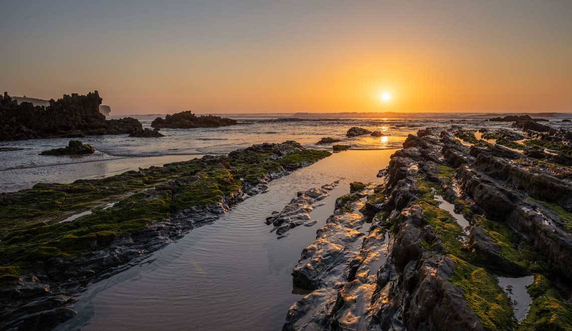 Sunset above tide rocks on Praia da Amoreira Portugal